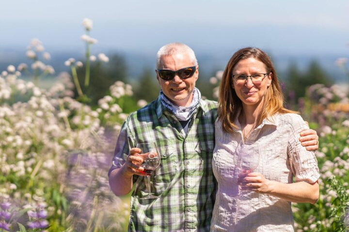 Happy couple in the vineyards wearing casual cotton button-down shirts while drinking Brooks Wine. 